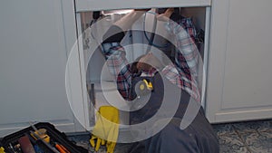 Plumber repairs a siphon leak in a kitchen sink