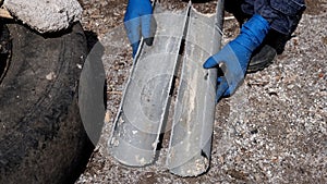 A plumber in rubber gloves cut a plastic sewer pipe lengthwise into two halves.