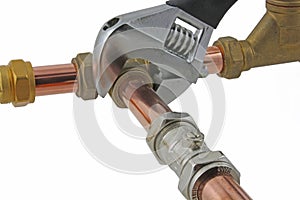 Plumber`s adjustable wrench tightening up copper pipework