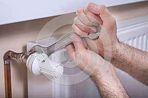 Plumber`s male hands hold a flat wrench by which they unscrew the temperature control valve. photo