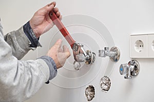 Plumber screwing plumbing fittings with an adjustable wrench.