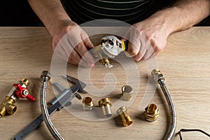 The plumber screws brass fitting onto the valve with a plumbing wrench. Hands of the master close up