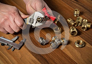 Plumber screws the brass fitting onto the valve with a plumbing wrench. Hands of the master close up