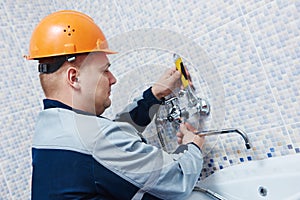 Plumber service. worker installing mixer tap