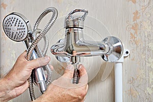 Plumber tightening fixing nut on flexible hose of shower head.