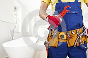 Plumber with tool belt standing in bathroom