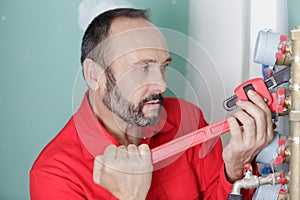 plumber with tool in hand repairing pipe