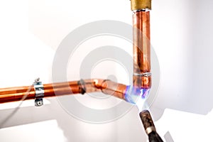 Plumber using blowtorch, propane gas torch for welding copper pipes photo