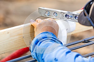 Plumber Using Level While Installing PVC Pipe At Construction Site