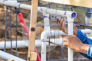 Plumber Using Level While Installing PVC Pipe At Construction Site