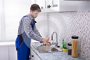 Plumber Using Plunger In Sink