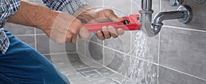 The plumber using a wrench to fix a leaking pipe in a bathroom. AI generated image