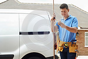 Plumber With Van Using Mobile Phone Outside House