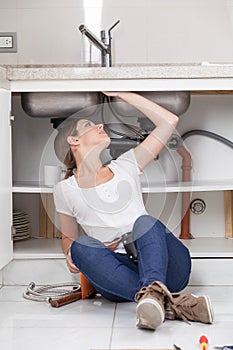 Plumber woman fixing the pipe of the kitchen