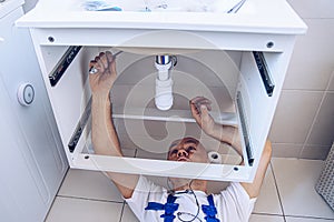 Plumber in work clothes is repairing or installing a bathroom sink