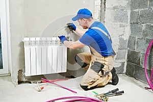 Plumber at work. Installing water heating radiator