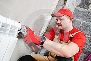 Plumber at work. Installing water heating radiator