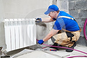 Plumber at work. Installing water heating radiator