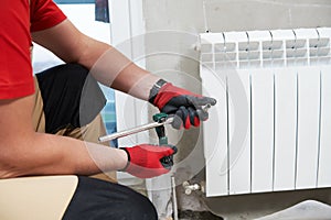 Plumber at work. Installing water heating radiator