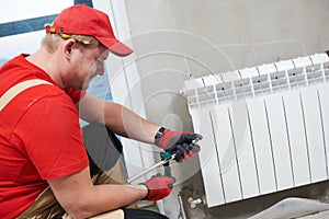 plumber at work. Installing water heating radiator