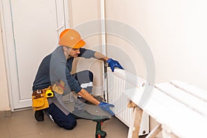 plumber at work. Installing water heating radiator