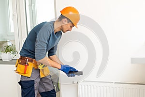 plumber at work. Installing water heating radiator