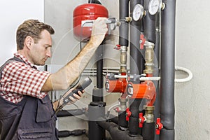 Plumber at work measures the temperature in a boiler room