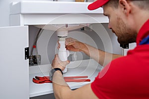 Plumber working in bathroom installing sink siphon