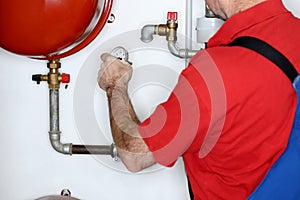 Plumber is working in a heating room