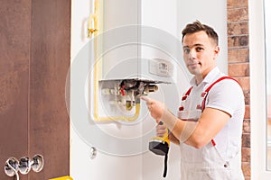 The plumber works with boiler at the kitchen