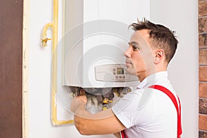 The plumber works with boiler at the kitchen