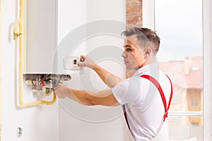 The plumber works with boiler at the kitchen