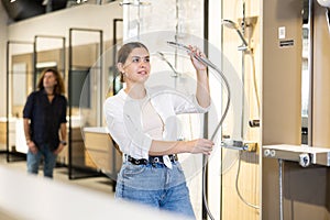 in plumbing department,woman examines shower head and quality of metal coating.