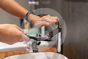 plumbing faucet repair concept. a plumber using a wrench unscrews the faucet aerator in the bathroom. concept plumber