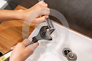 plumbing faucet repair concept. a plumber using a wrench unscrews the faucet aerator in the bathroom. concept plumber