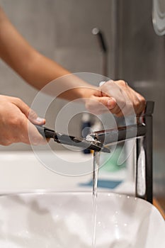 plumbing faucet repair concept. a plumber using a wrench unscrews the faucet aerator in the bathroom. concept plumber