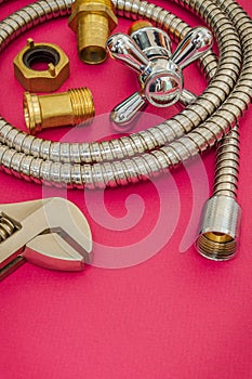 Plumbing materials faucet, tool, fittings and hose on red background are used for replacement in the shower