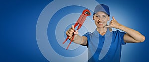 Plumbing services - woman plumber with wrench showing phone call gesture on blue background with copy space