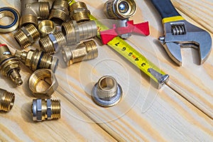 Plumbing spare parts and tool closeup on woodmen boards. Brass fittings for replacement or repair