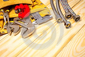 Plumbing tools in the bag and hoses on wooden boards are used to replace or repair