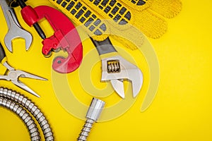 Plumbing tools and gloves for connecting water hoses on a yellow desktop