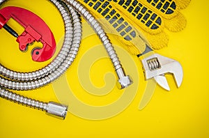 Plumbing tools and gloves for connecting water hoses on yellow desktop