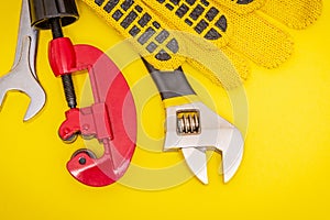 Plumbing tools and gloves for connecting water pipes on a yellow desktop