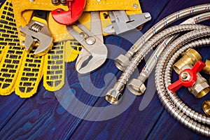 Plumbing tools in the yellow bag and spare parts on blue wooden boards are used to replace or repair