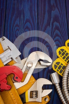 Plumbing tools in the yellow bag and spare parts on blue wooden boards are used to replace or repair