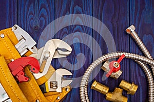 Plumbing tools in the yellow bag and spare parts on blue wooden boards are used to replace or repair