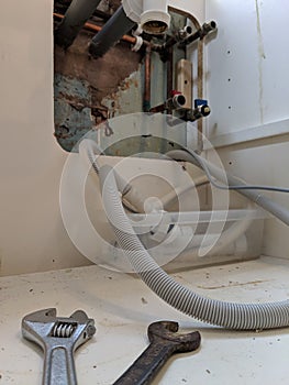 The plumbing underneath a kitchen sink with close up of spanners