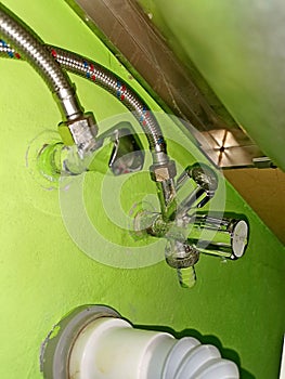 Plumbing valves under the kitchen counter, with hoses and waste pipe