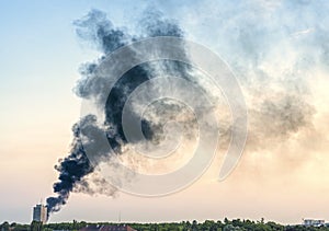 Plume of smoke from a fire above city at sunset