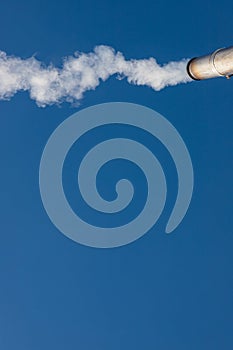 a plume of smoke or steam from an industrial smokestack on a clear blue sky